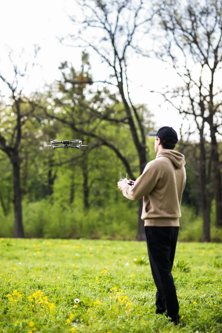 Piloto no parque com o drone voando à frente