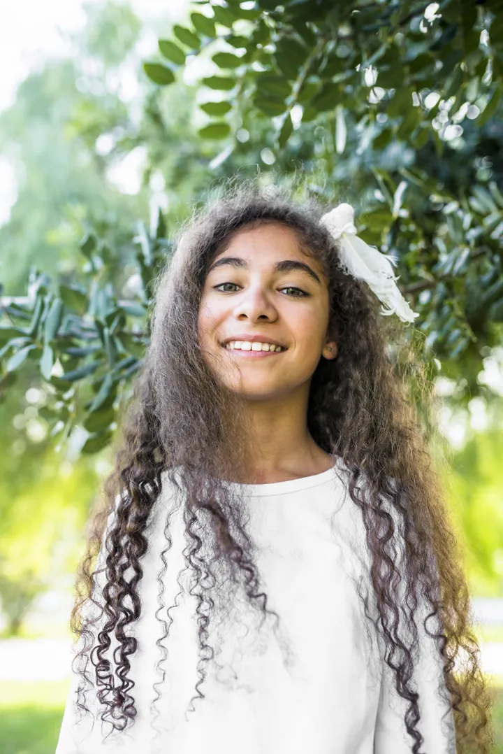 Menina sorrindo ao ar livre, entre folhas